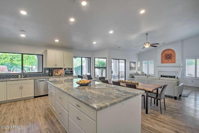 kitchen featuring lofted ceiling, white cabinetry, a center island, dishwasher, and light hardwood / wood-style floors