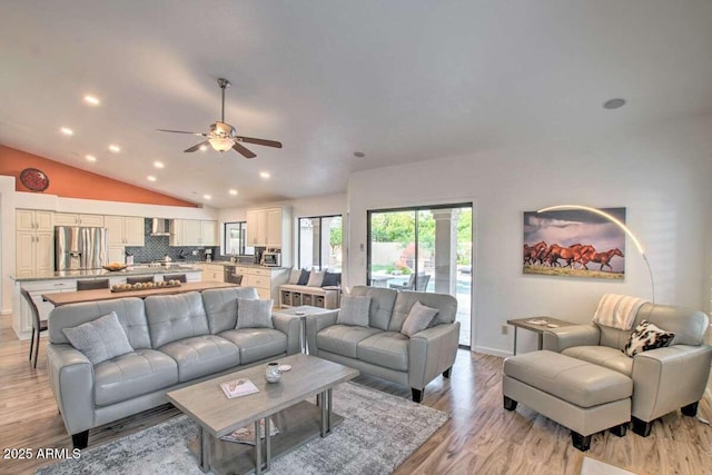 living room featuring ceiling fan, lofted ceiling, and light wood-type flooring