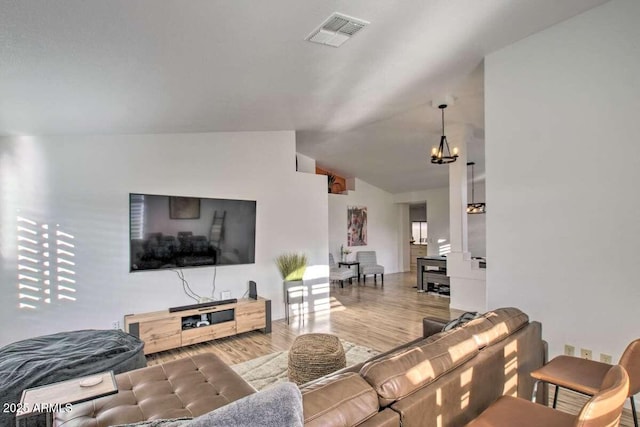 living room featuring lofted ceiling, a chandelier, and hardwood / wood-style floors