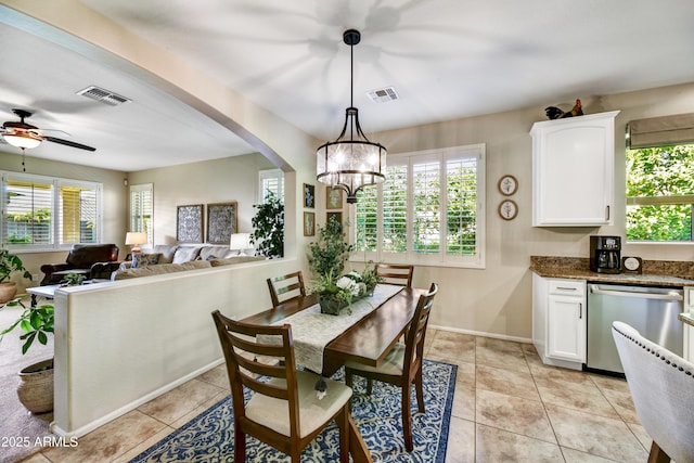 tiled dining space with plenty of natural light and ceiling fan with notable chandelier