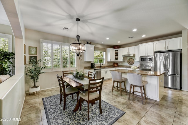 tiled dining space with an inviting chandelier and sink