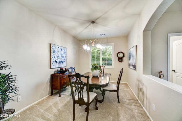 carpeted dining room featuring an inviting chandelier