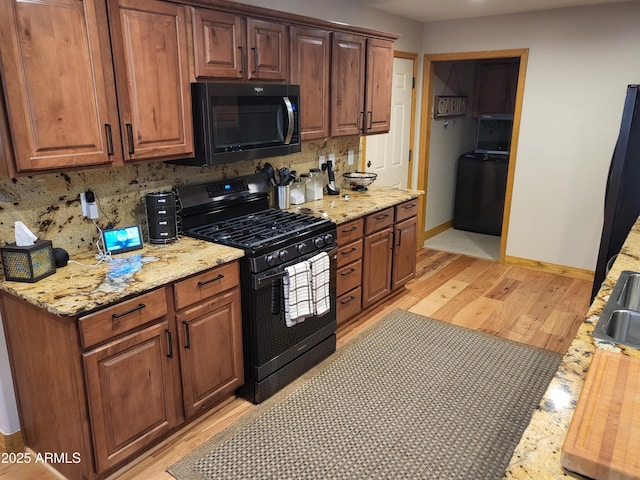 2978 Timberline Rd, Pinetop, AZ 85935 - kitchen with backsplash, baseboards, black gas range oven, washer / dryer, and light wood-style flooring