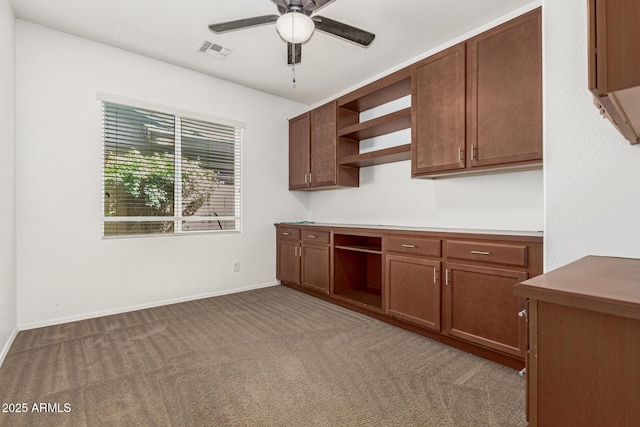 kitchen featuring carpet, open shelves, visible vents, built in study area, and ceiling fan