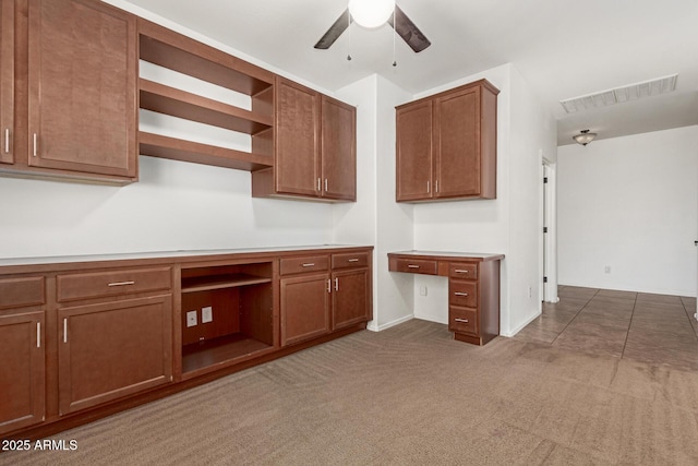 kitchen featuring ceiling fan, visible vents, open shelves, built in desk, and carpet