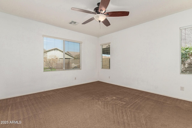 carpeted empty room featuring a ceiling fan and visible vents