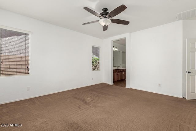 carpeted spare room featuring baseboards, visible vents, and a ceiling fan