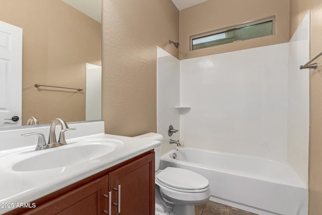 bathroom featuring a textured wall, bathing tub / shower combination, vanity, and toilet