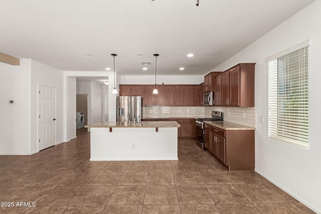 kitchen featuring stainless steel appliances, washer / dryer, decorative backsplash, and a kitchen bar