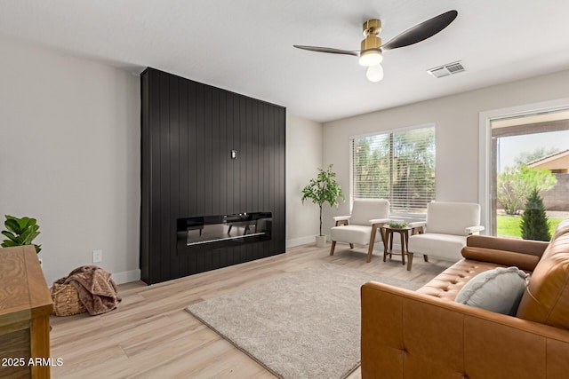 33287 N Windmill Run, San Tan Valley, AZ 85144 - living area with light wood-style flooring, ceiling fan, baseboards, and a fireplace