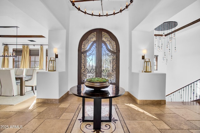 foyer entrance featuring french doors, a high ceiling, stone tile flooring, and baseboards