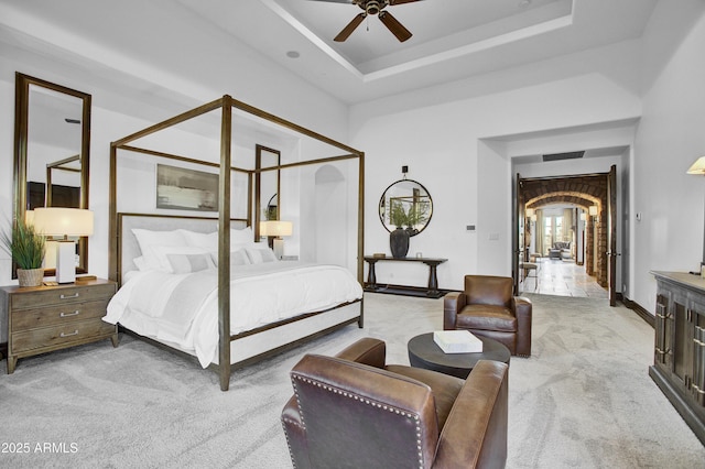 bedroom featuring light carpet, ceiling fan, and a raised ceiling