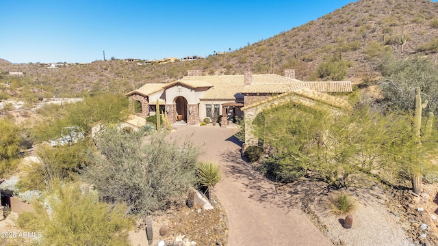 exterior space with dirt driveway, stucco siding, a mountain view, fence, and stone siding