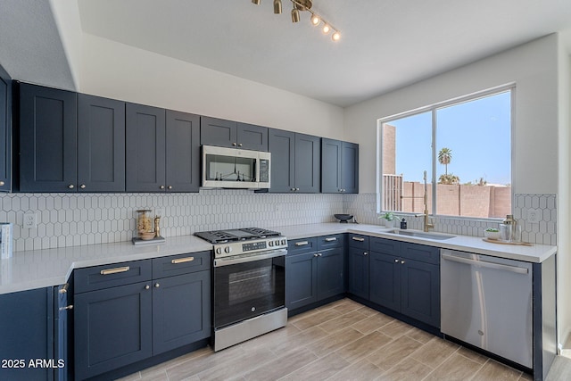 kitchen with a sink, light wood-style floors, light countertops, tasteful backsplash, and appliances with stainless steel finishes