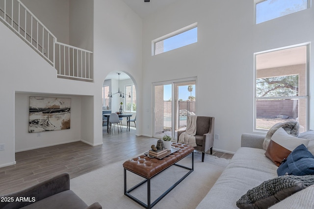 living area featuring a healthy amount of sunlight, wood finished floors, and a high ceiling