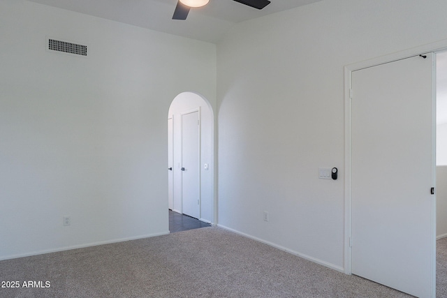 carpeted empty room featuring a ceiling fan, baseboards, visible vents, vaulted ceiling, and arched walkways