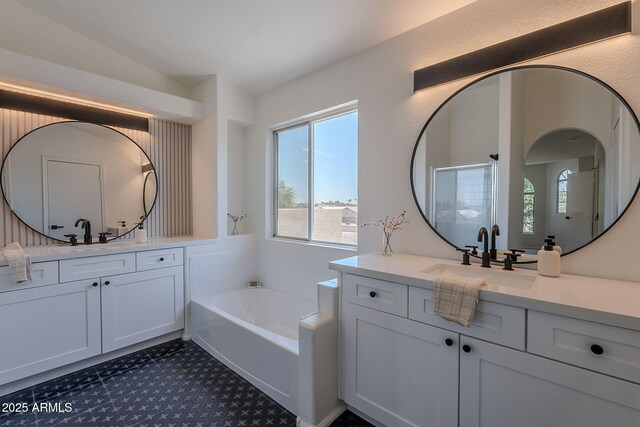 full bath featuring a garden tub, two vanities, and a sink