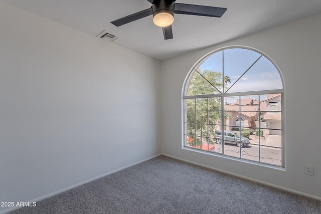 carpeted spare room featuring baseboards, visible vents, and a ceiling fan