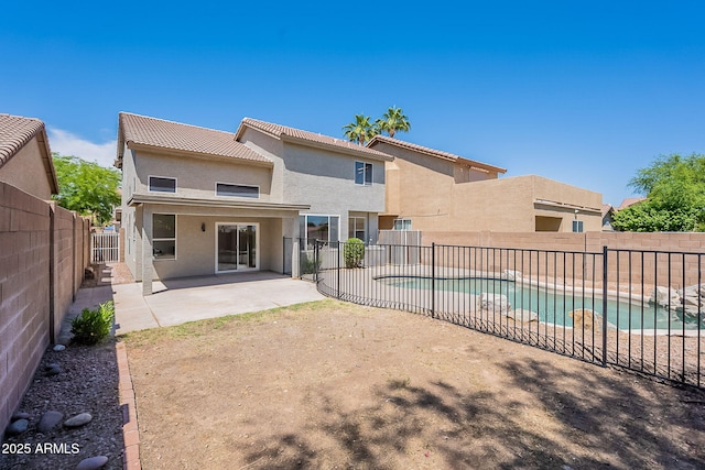 rear view of property featuring a tiled roof, a fenced in pool, a patio area, stucco siding, and a fenced backyard