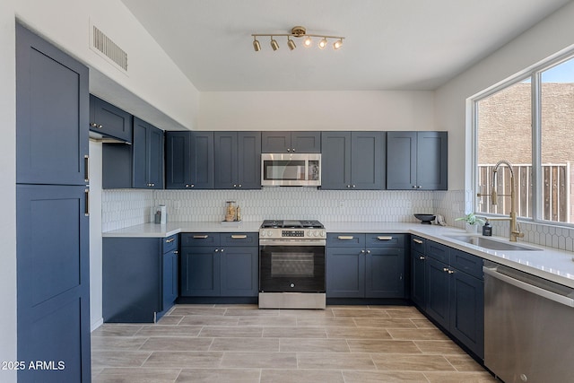 kitchen featuring a sink, stainless steel appliances, visible vents, backsplash, and light countertops