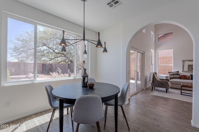 dining space with arched walkways, visible vents, and plenty of natural light