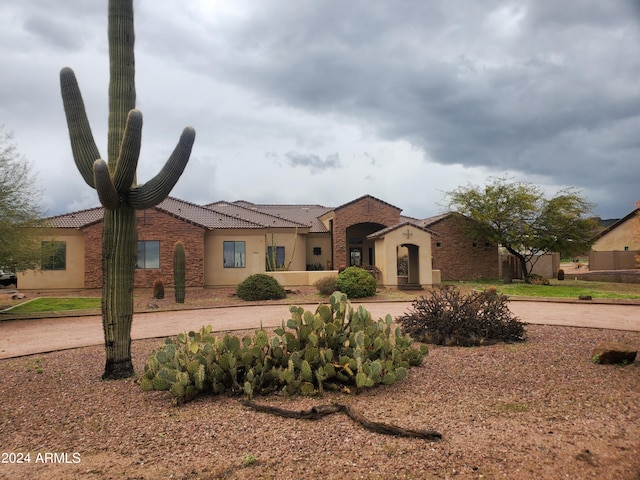 mediterranean / spanish home featuring a tile roof and stucco siding