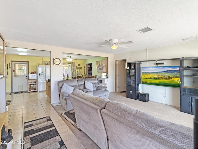 living room featuring light tile patterned floors, a textured ceiling, visible vents, and a ceiling fan