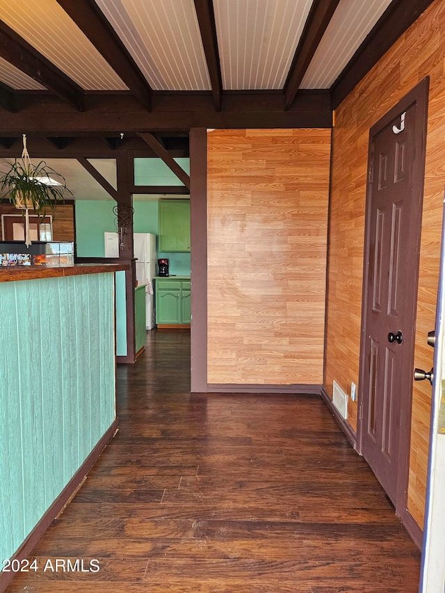 hallway featuring beamed ceiling, dark hardwood / wood-style floors, and wooden walls