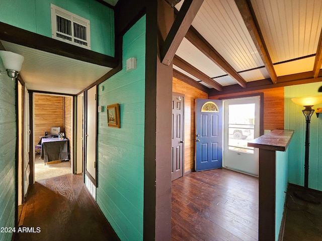 hall featuring lofted ceiling with beams, dark hardwood / wood-style floors, and wooden walls