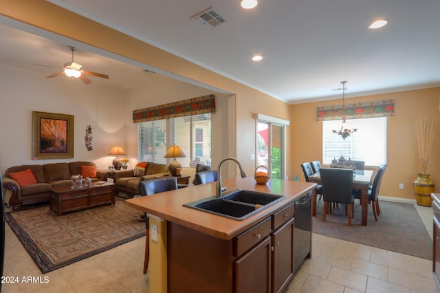 kitchen with a healthy amount of sunlight, sink, ceiling fan with notable chandelier, and an island with sink