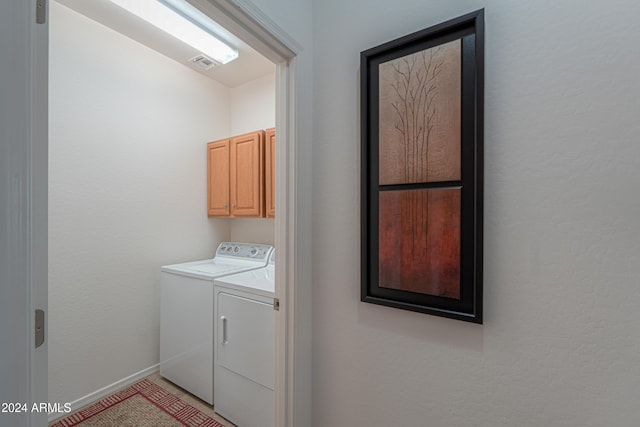 laundry room featuring washing machine and dryer and cabinets