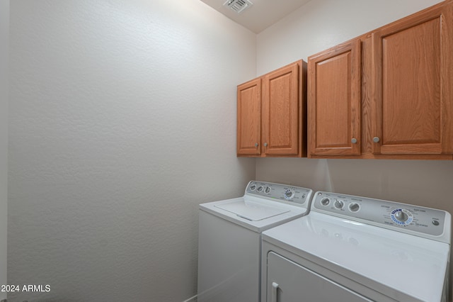 clothes washing area featuring washer and clothes dryer and cabinets