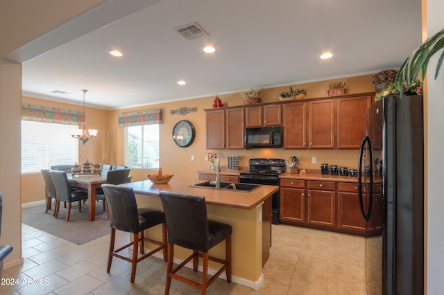 kitchen featuring black appliances, sink, an island with sink, a kitchen bar, and decorative light fixtures