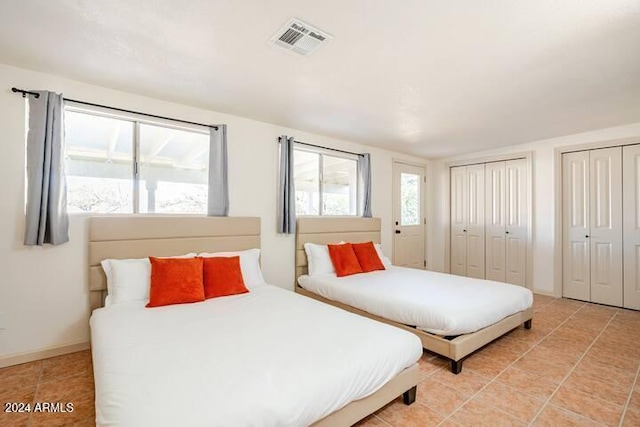 bedroom featuring light tile patterned floors and two closets