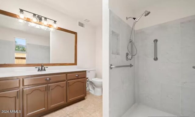 bathroom with vanity, toilet, and tiled shower