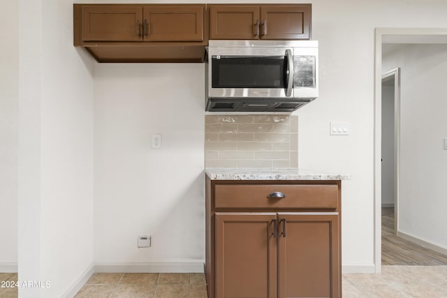 kitchen with backsplash, light stone counters, and light tile patterned floors