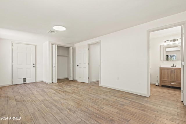 unfurnished bedroom featuring ensuite bathroom and light wood-type flooring