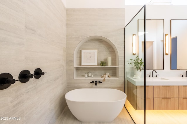 full bathroom with a soaking tub, tile walls, and vanity