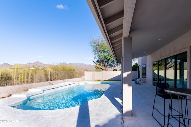 view of pool featuring a patio area, a fenced in pool, a mountain view, and a fenced backyard