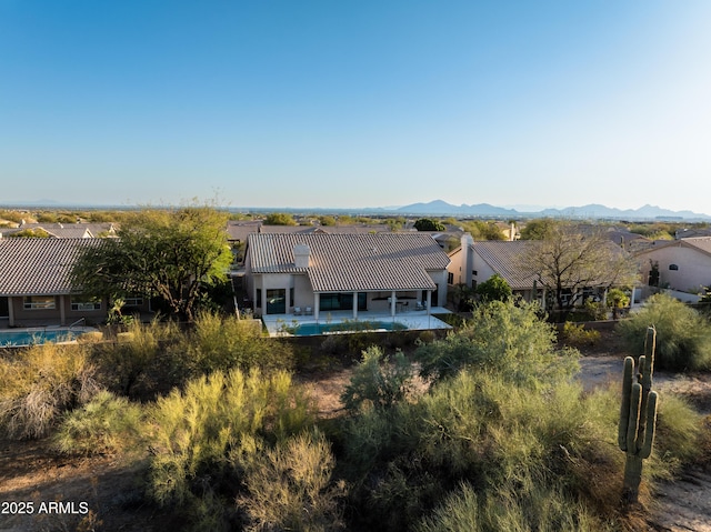 back of property featuring a tiled roof, stucco siding, a mountain view, and a patio