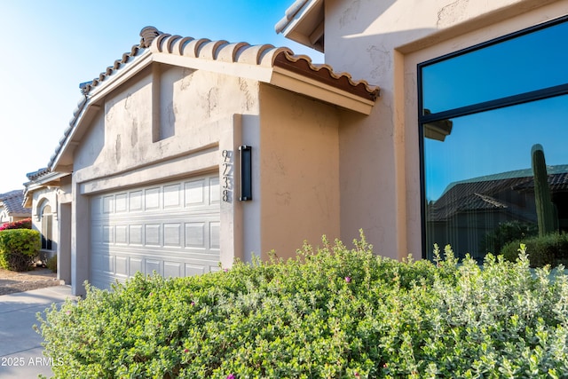 view of home's exterior featuring stucco siding, a garage, and a tiled roof