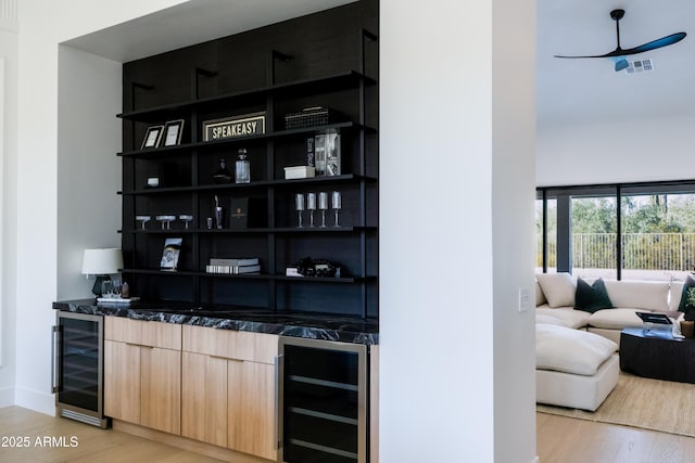 bar featuring light wood-type flooring, wet bar, and beverage cooler