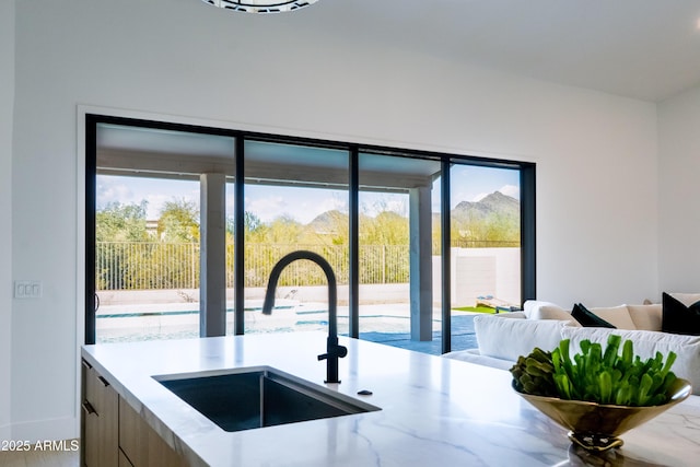 kitchen featuring open floor plan, light stone countertops, modern cabinets, and a sink