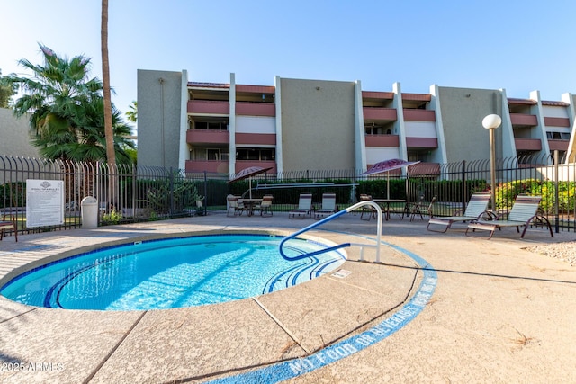 community pool with fence and a patio area