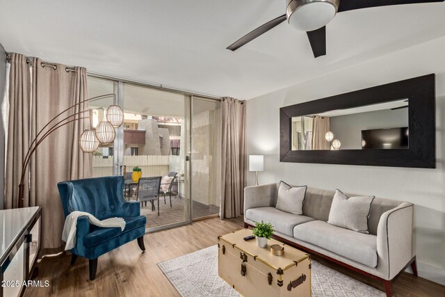 living room featuring wood finished floors, a ceiling fan, and a wall of windows