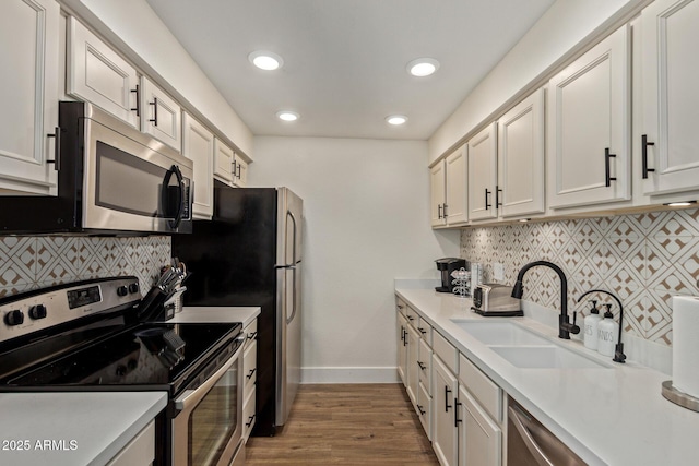 kitchen with appliances with stainless steel finishes, a sink, baseboards, tasteful backsplash, and recessed lighting
