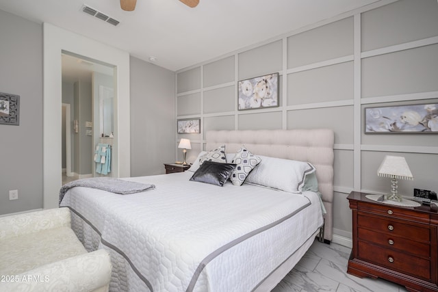 bedroom featuring visible vents, marble finish floor, a decorative wall, and a ceiling fan