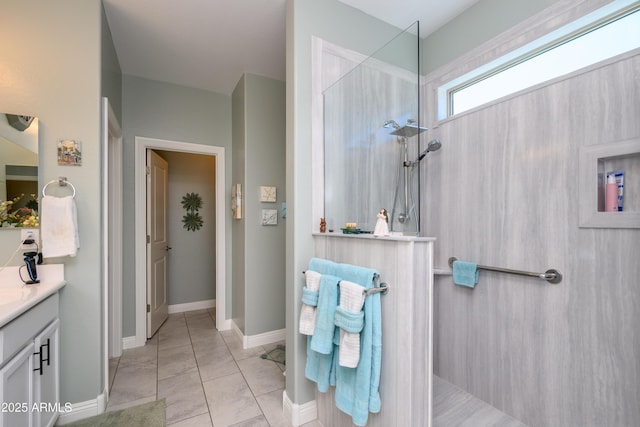 full bathroom with vanity, tile patterned floors, a walk in shower, and baseboards