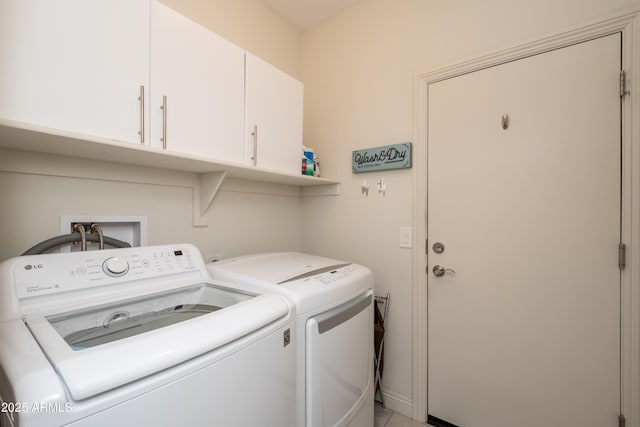 clothes washing area featuring cabinet space and washer and clothes dryer