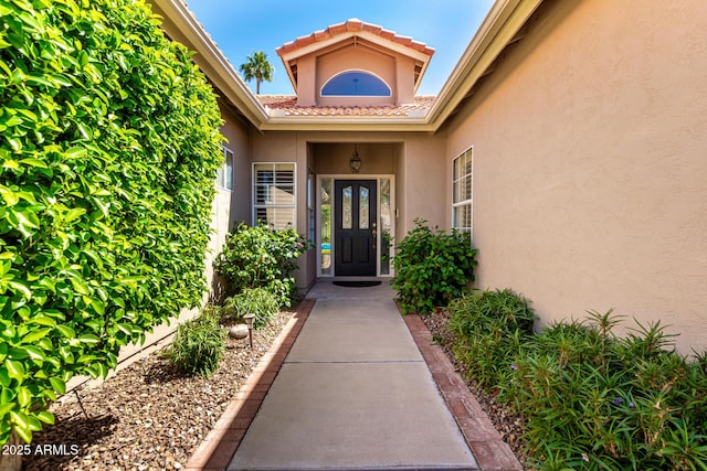 property entrance with stucco siding and a tile roof